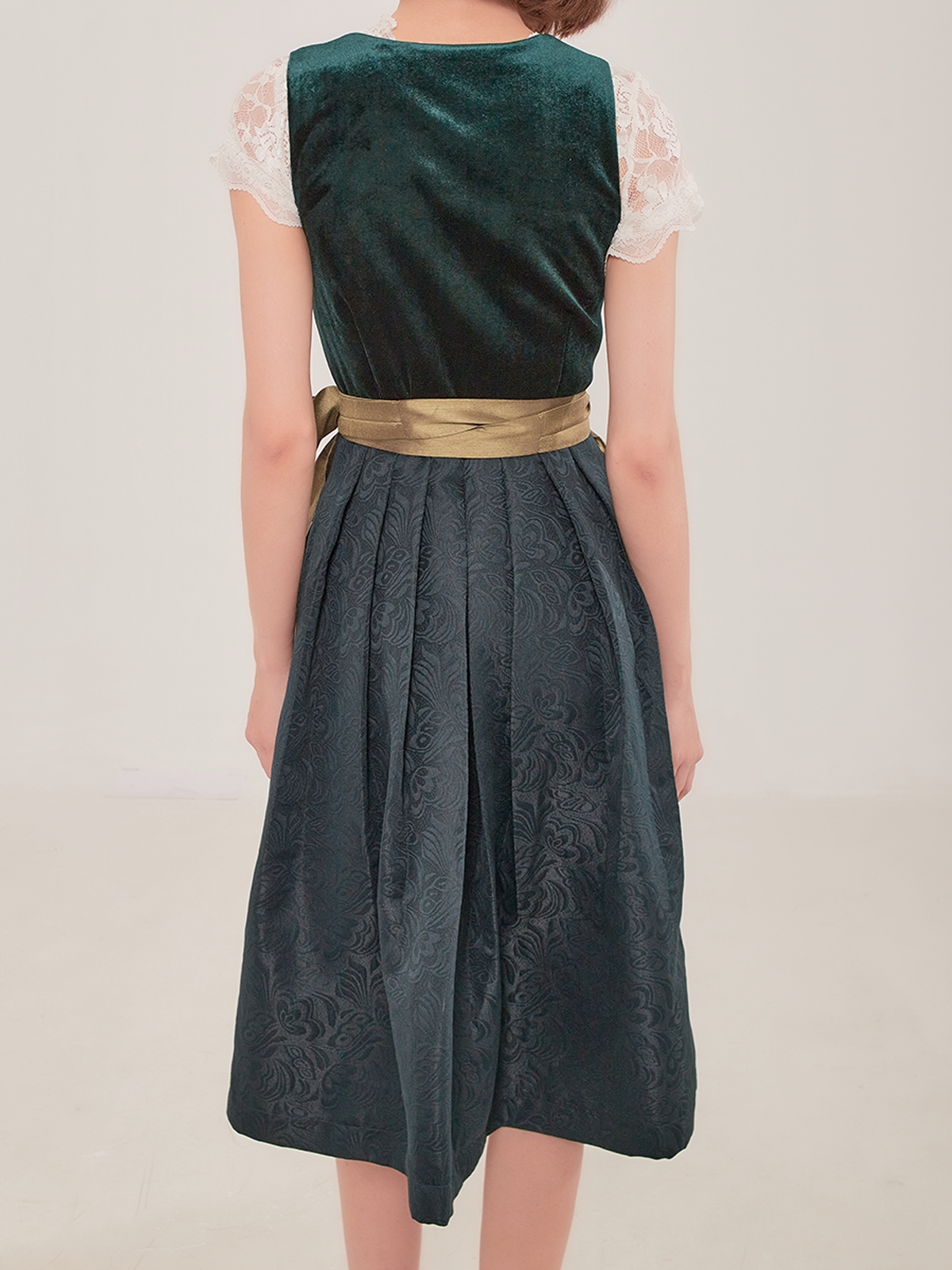 Ein elegantes grünes Dirndl mit traditioneller Schürze und modernen Accessoires